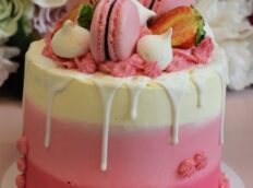 roze-lichtroze-wit-laagjes-taart-met-witte-drip-roze-macarons-aardbeien-en-meringue